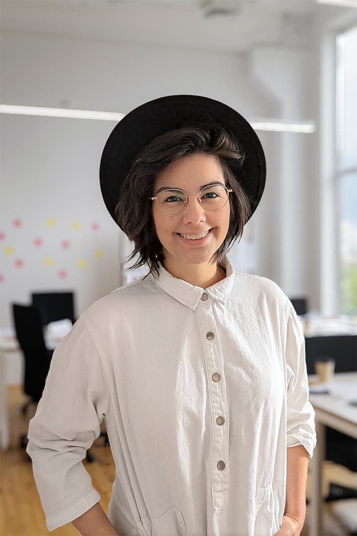 Ilana Luong, souriante, chapeau noir et chemise claire, dans un espace de travail lumineux